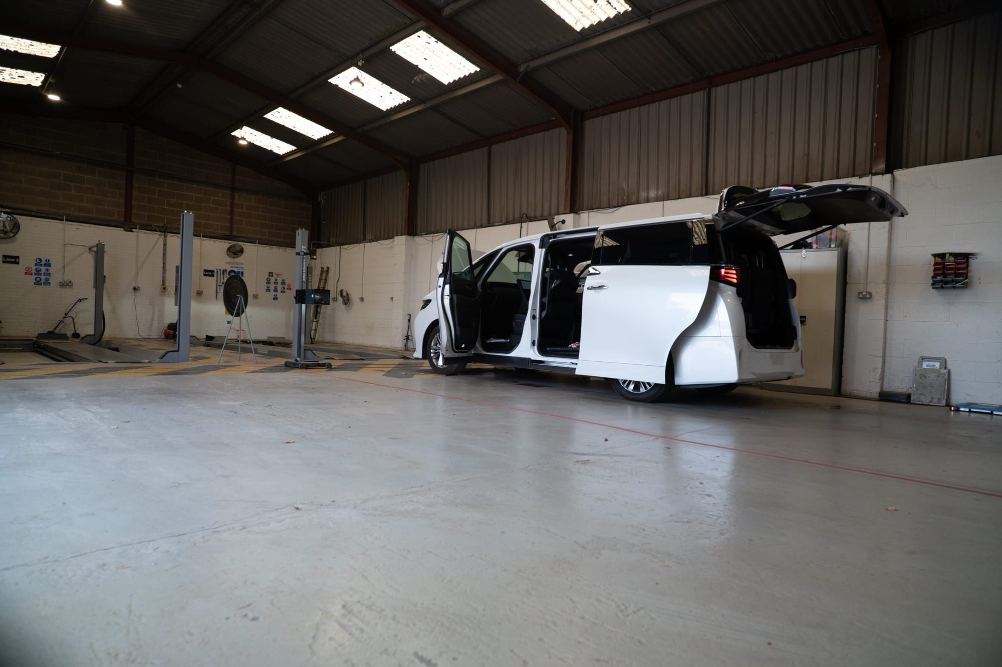 A white Toyota Alphard with its doors and tailgate open in My Car Import's workshop