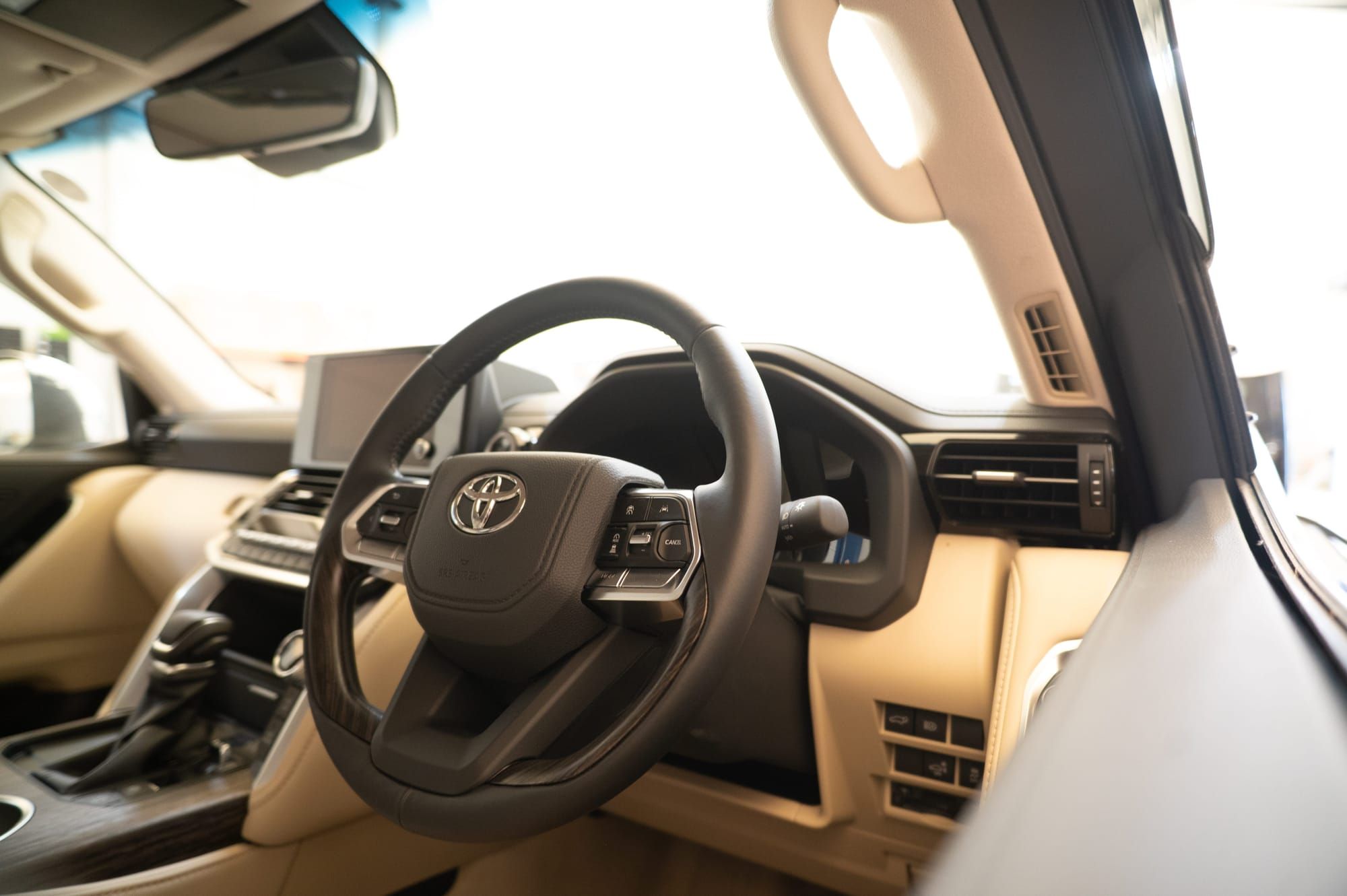 The right-hand-drive dashboard and steering wheel of a Toyota Alphard, with cream leather trim