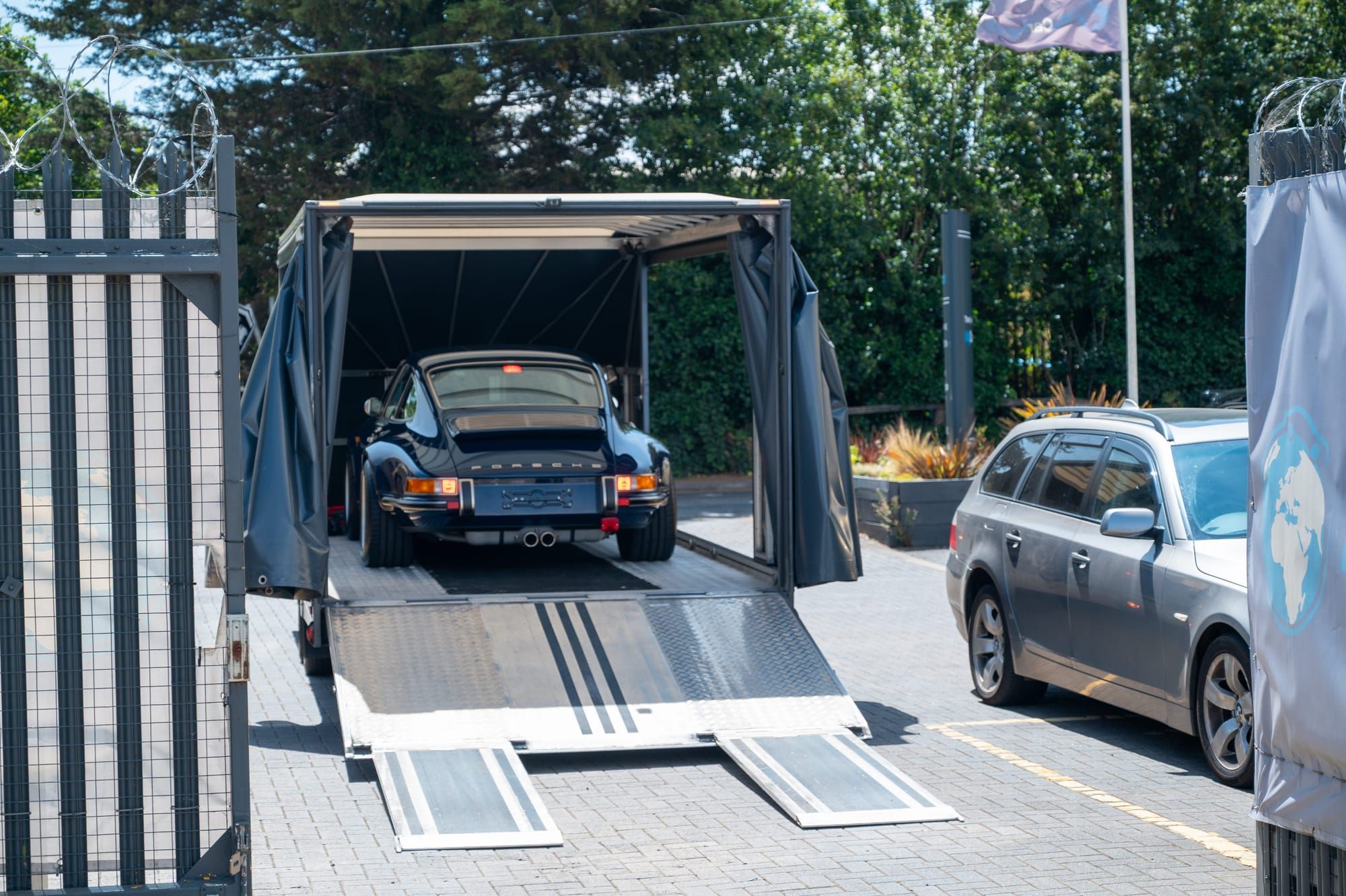 A classic Porsche 911 loaded in a My Car Import enclosed transporter, ramps down