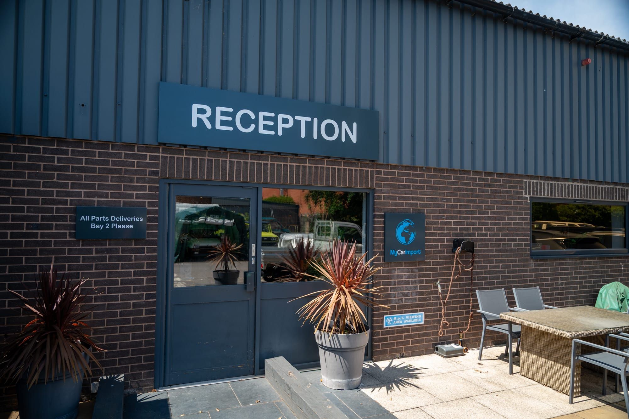 The reception entrance at My Car Import, with planters and outdoor seating