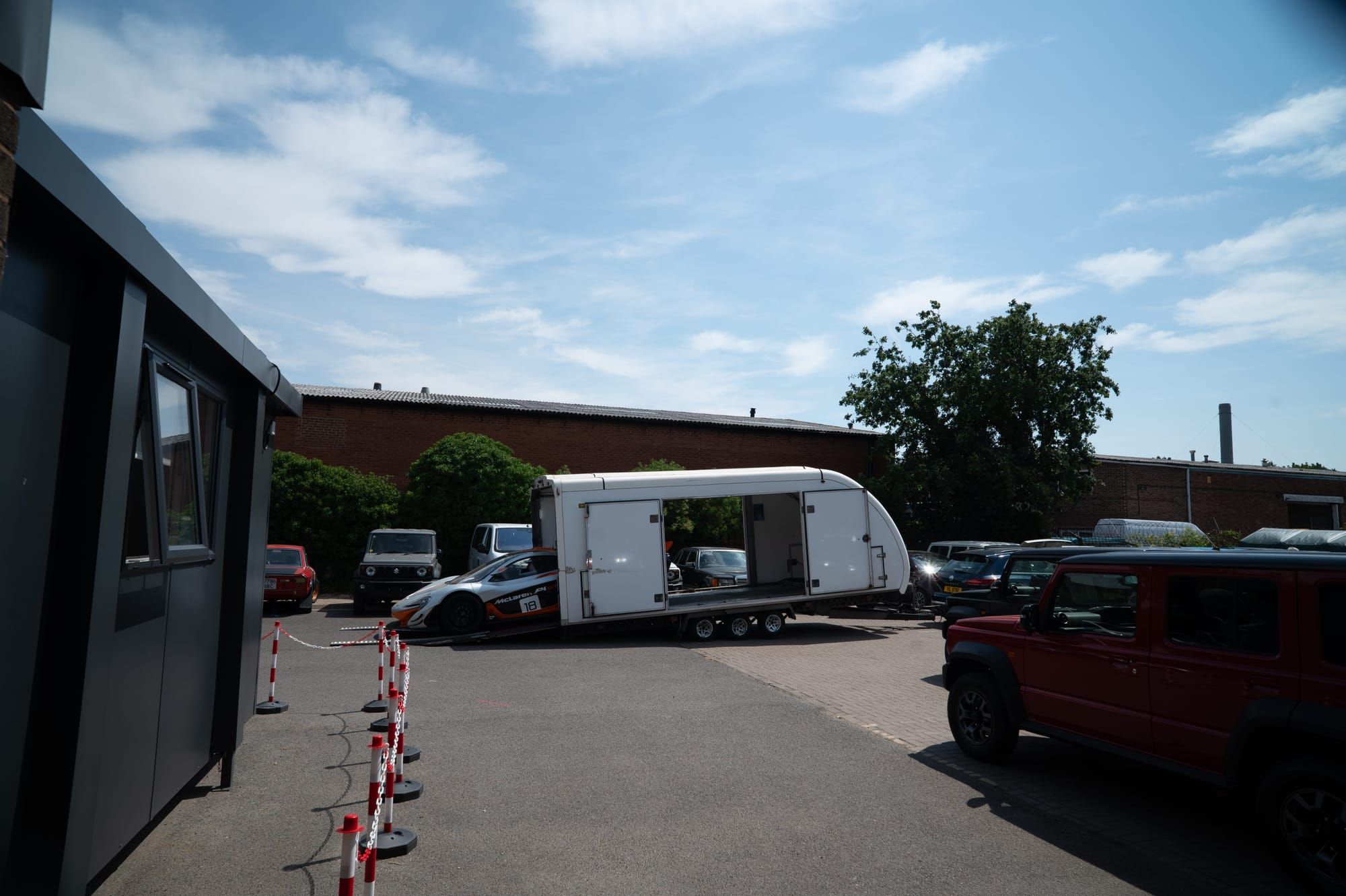 My Car Import's enclosed transporter parked outside the office, with cars alongside